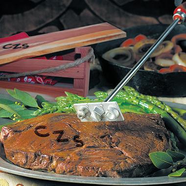 Branding Irons in example, branding a cooked steak with the initials C Z S.