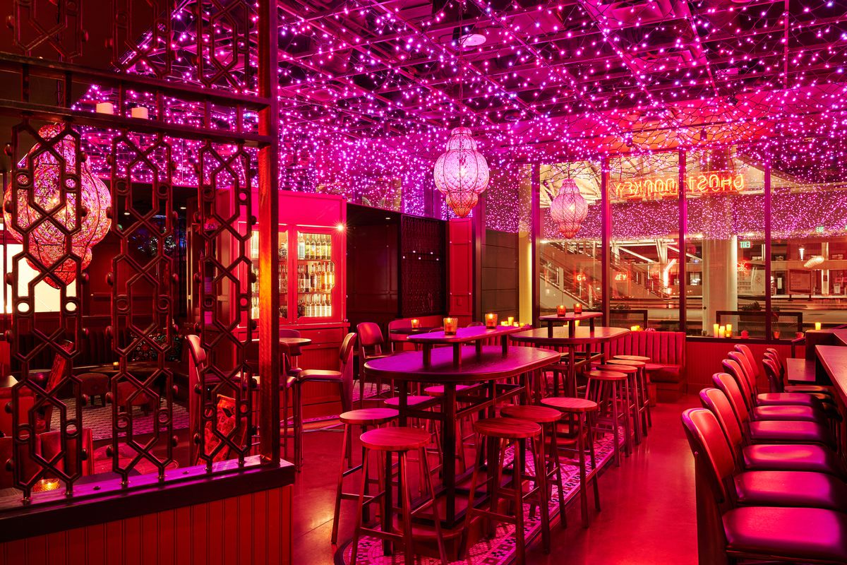  A darkened restaurant with hundreds of pink neon lights hanging from the ceiling giving the room an electric glow.