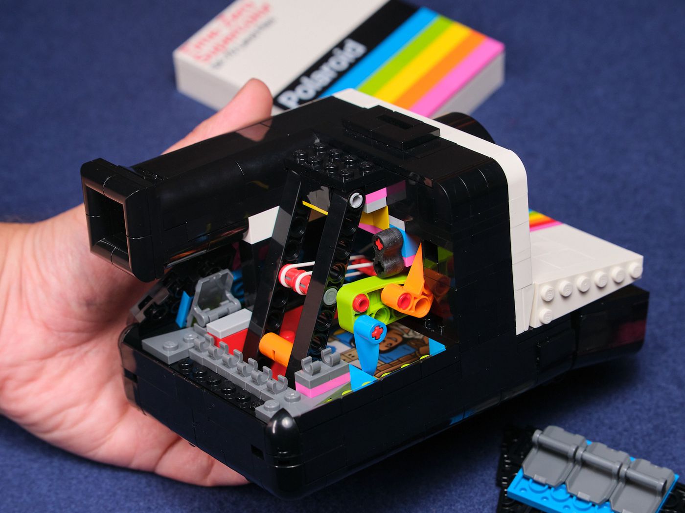 The final mechanism uses a simple orange and green linkage to raise a blue tooth, which lets the arm shoot forward. Here, you can see it encased in the Polaroid’s pyramid-like rear shell.