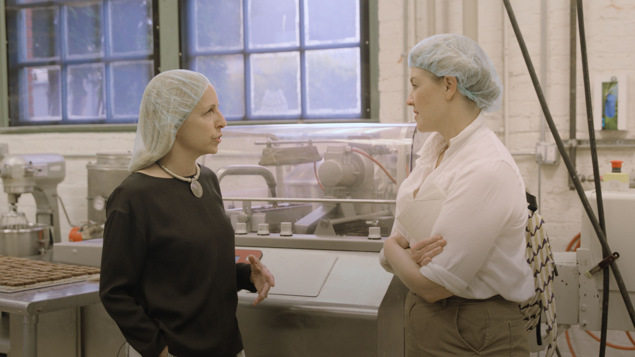 jeni in a hairnet talking to another woman